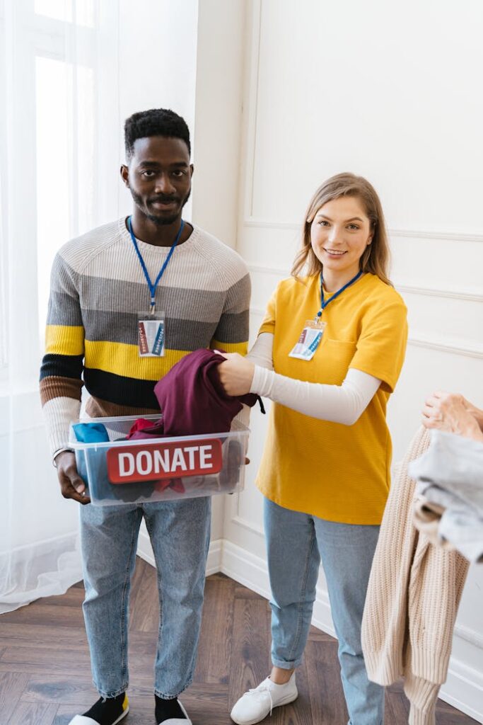 Diverse young volunteers collecting clothes for donation in a bright indoor setting.